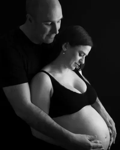 A man is holding a pregnant woman 's belly in a black and white photo