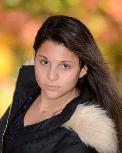The girl is wearing a black jacket with a white fur hood