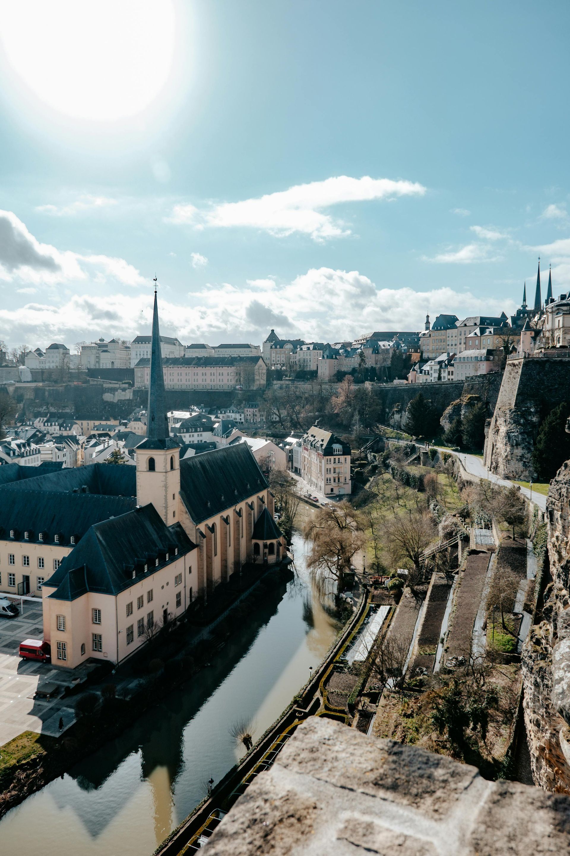 Cityscape with church steeple, river, buildings on cliffs, sunny blue sky.