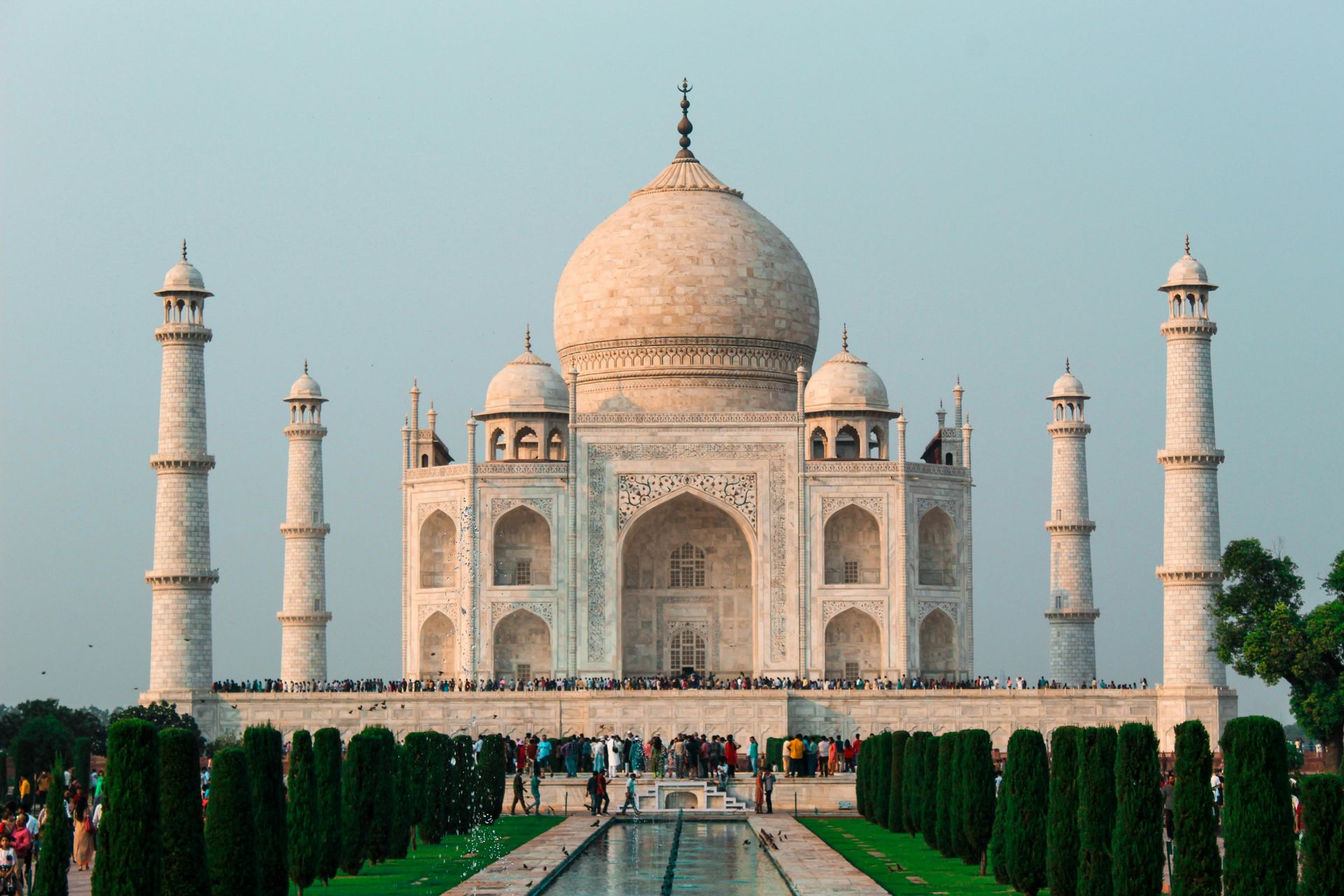 Taj Mahal, white marble mausoleum in Agra, India, with central dome and minarets, reflecting in water.
