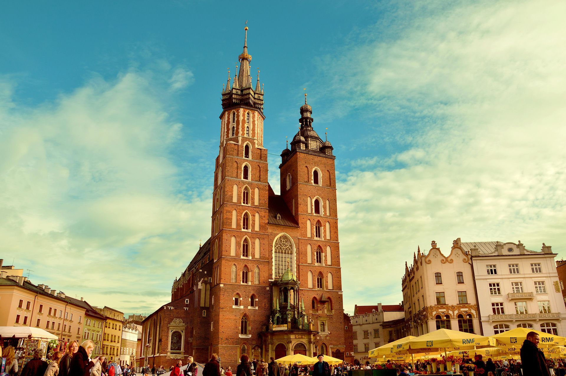 St. Mary's Basilica in Kraków, Poland, a red-brick Gothic church with tall towers against a blue sky.
