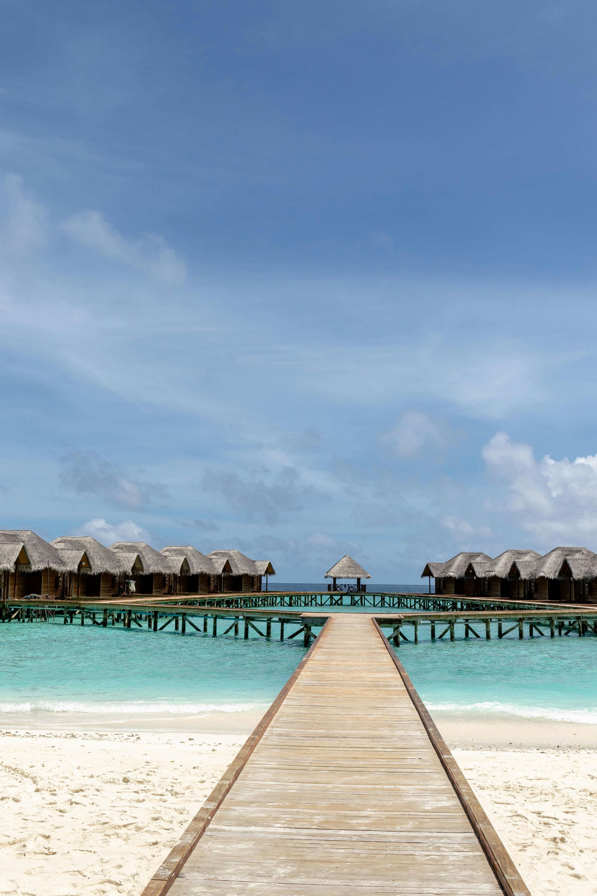 Tropical island with turquoise water, white sand beach, palm trees, and clear blue sky.