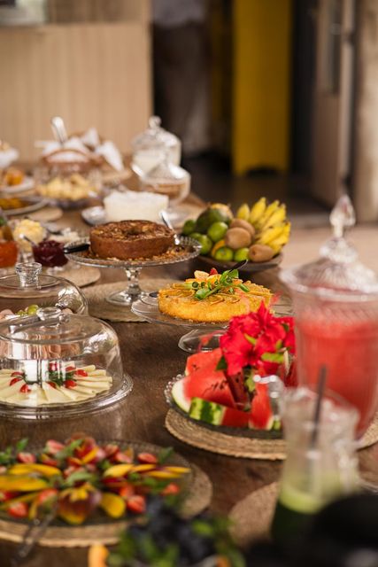 Café da manhã servido ao ar livre: frutas, carnes, queijos, sucos, pães, doces e ovos mexidos salgados.