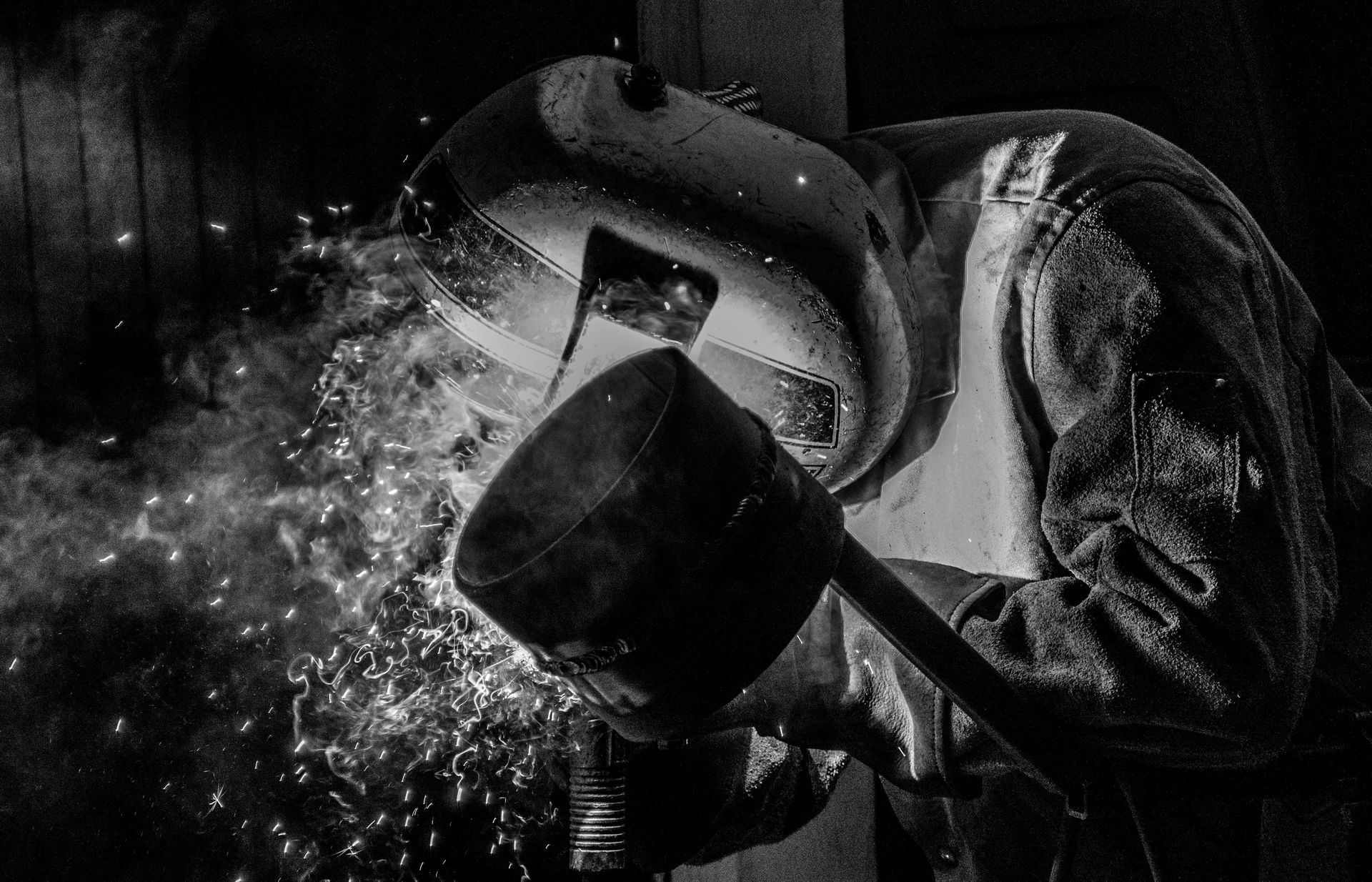 A black and white photo of a person blowing water out of a bucket.