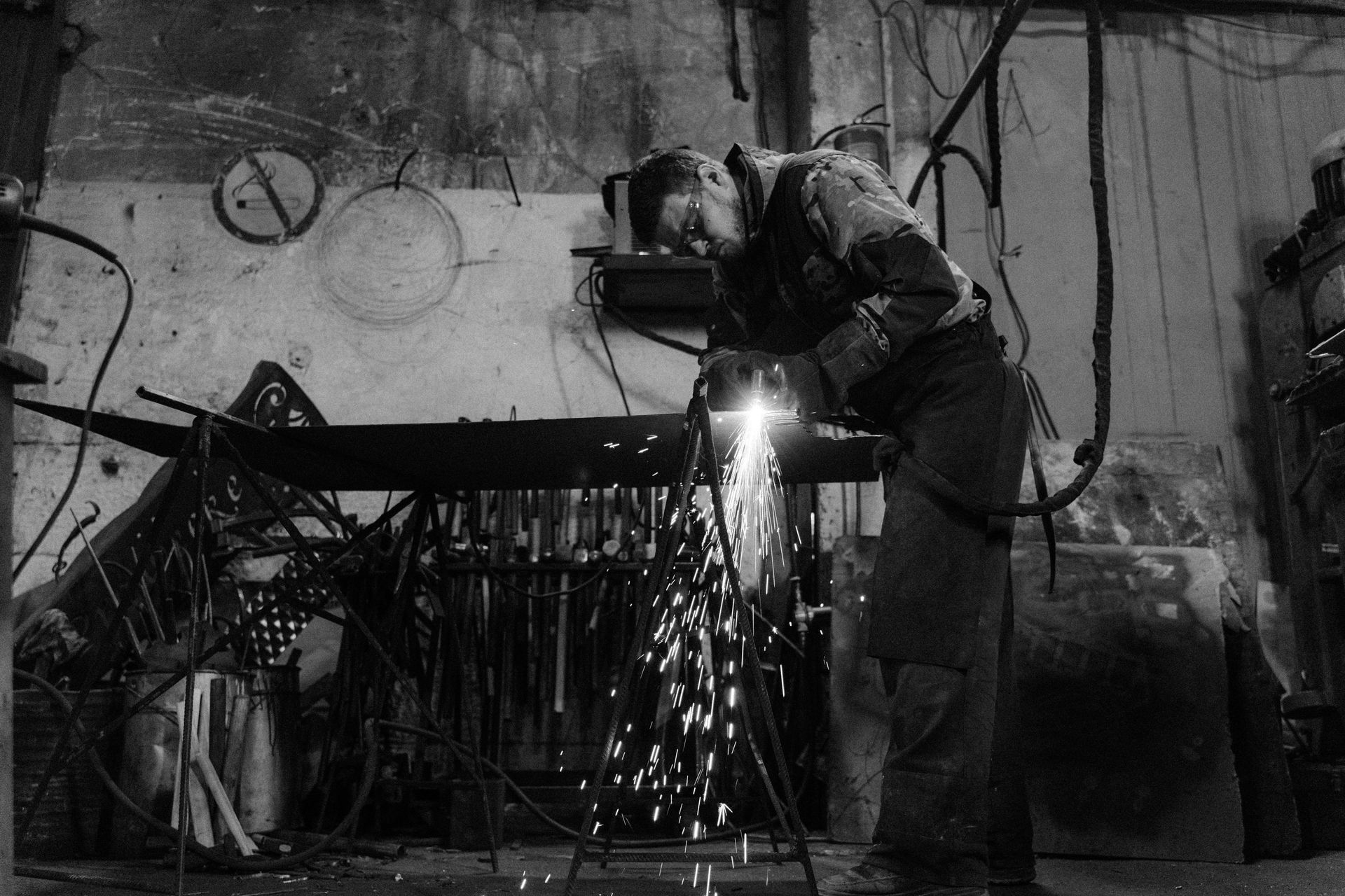 A man is welding a piece of metal in a black and white photo.