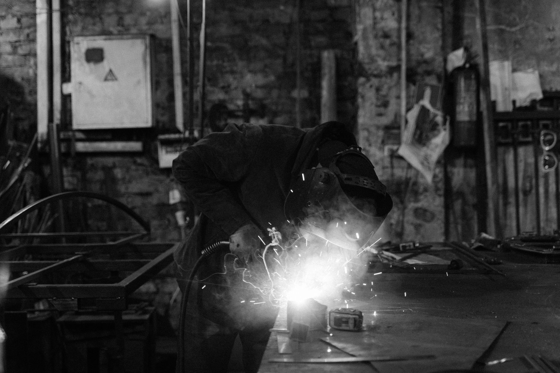 A man is welding a piece of metal in a black and white photo.