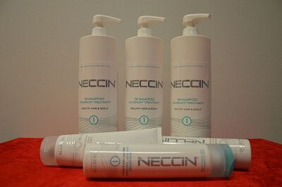 Tre NECCIN pumpeflasker og en tube produkt på en rød overflade mod en almindelig baggrund