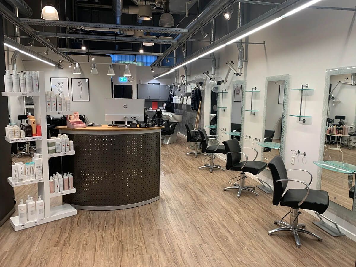 Moderne salonindretning med stylingstole, spejle, diske og trægulve