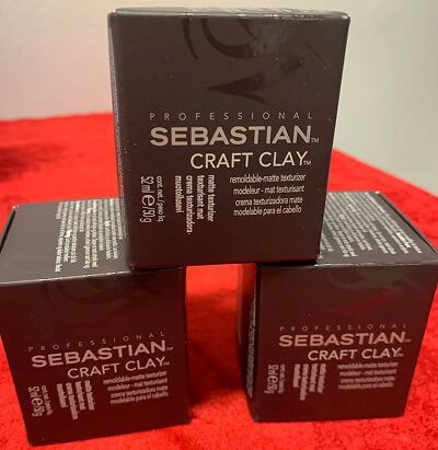 Tre mørkebrune Sebastian Craft Clay-æsker stablet på en rød overflade