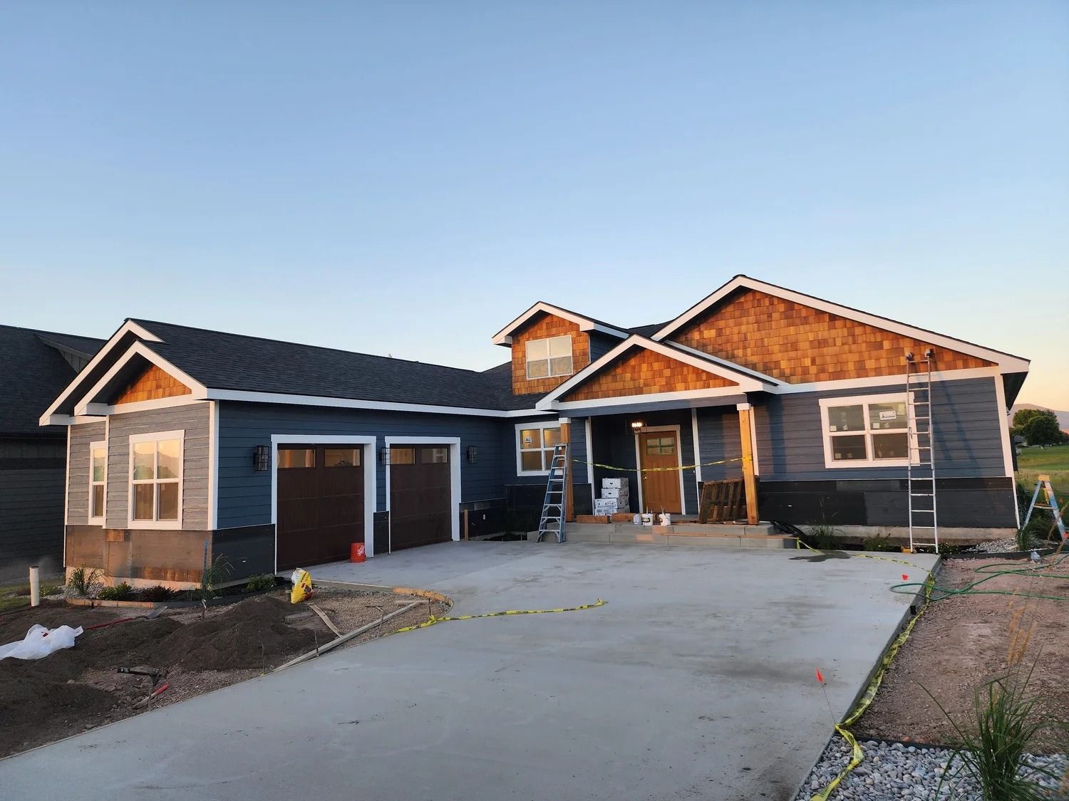 Newly built dark blue house with a concrete driveway and attached garage at sunset