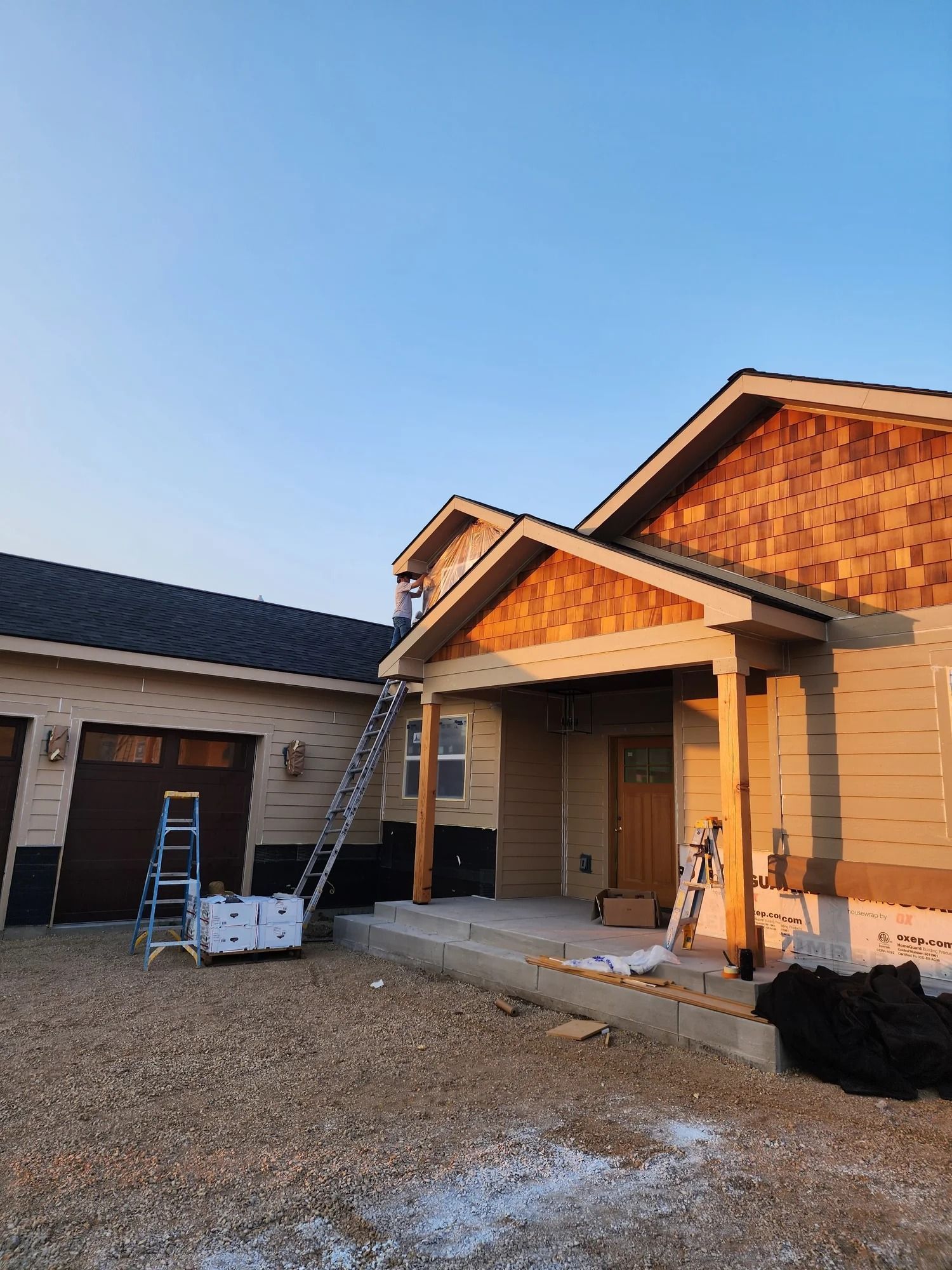 House under construction with ladders, a porch, and building materials at sunset
