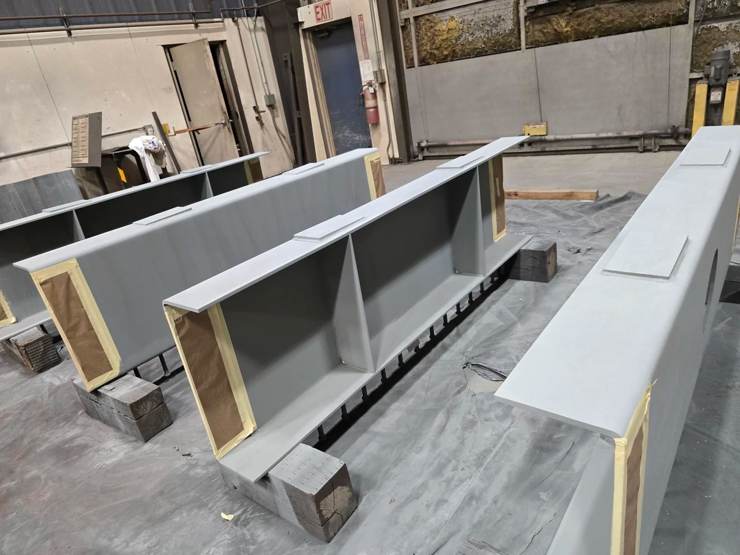 Rows of long white beams on concrete blocks in an industrial workshop