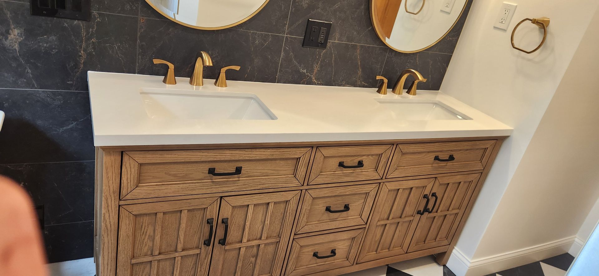 Modern bathroom vanity with double sink, white countertop, wicker-front cabinets, and round mirror