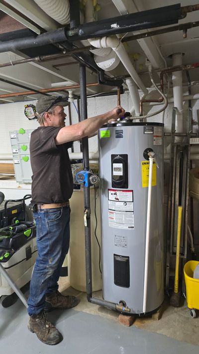 Technician inspecting a water heater in a basement utility room