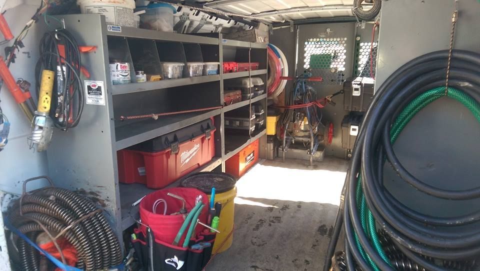 Organized work van interior with shelves, tools, bins, and coiled hoses on both sides