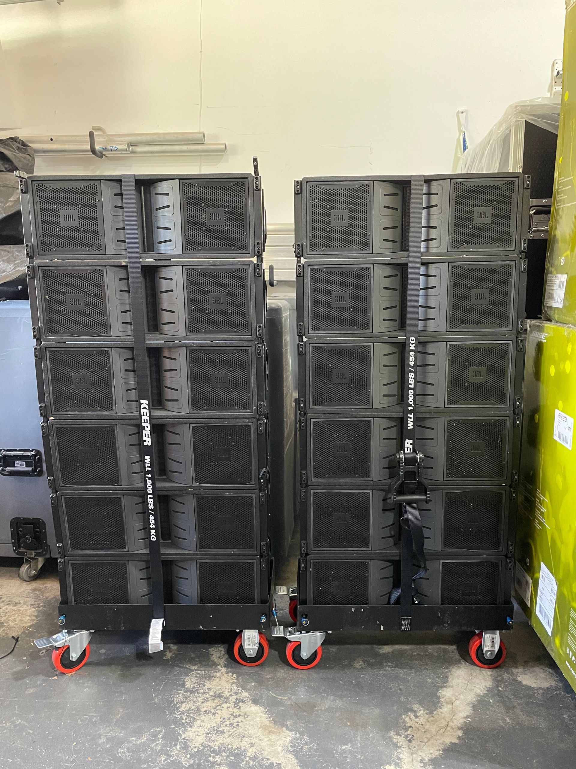 Two stacks of speakers are sitting on wheels in a room.