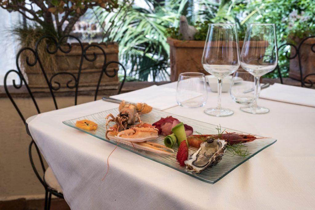 Un piatto di cibo è appoggiato su un tavolo accanto a dei bicchieri di vino.