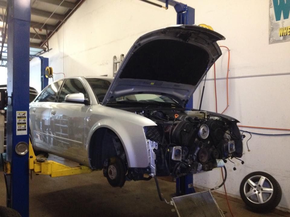 A silver car is on a lift with the hood open