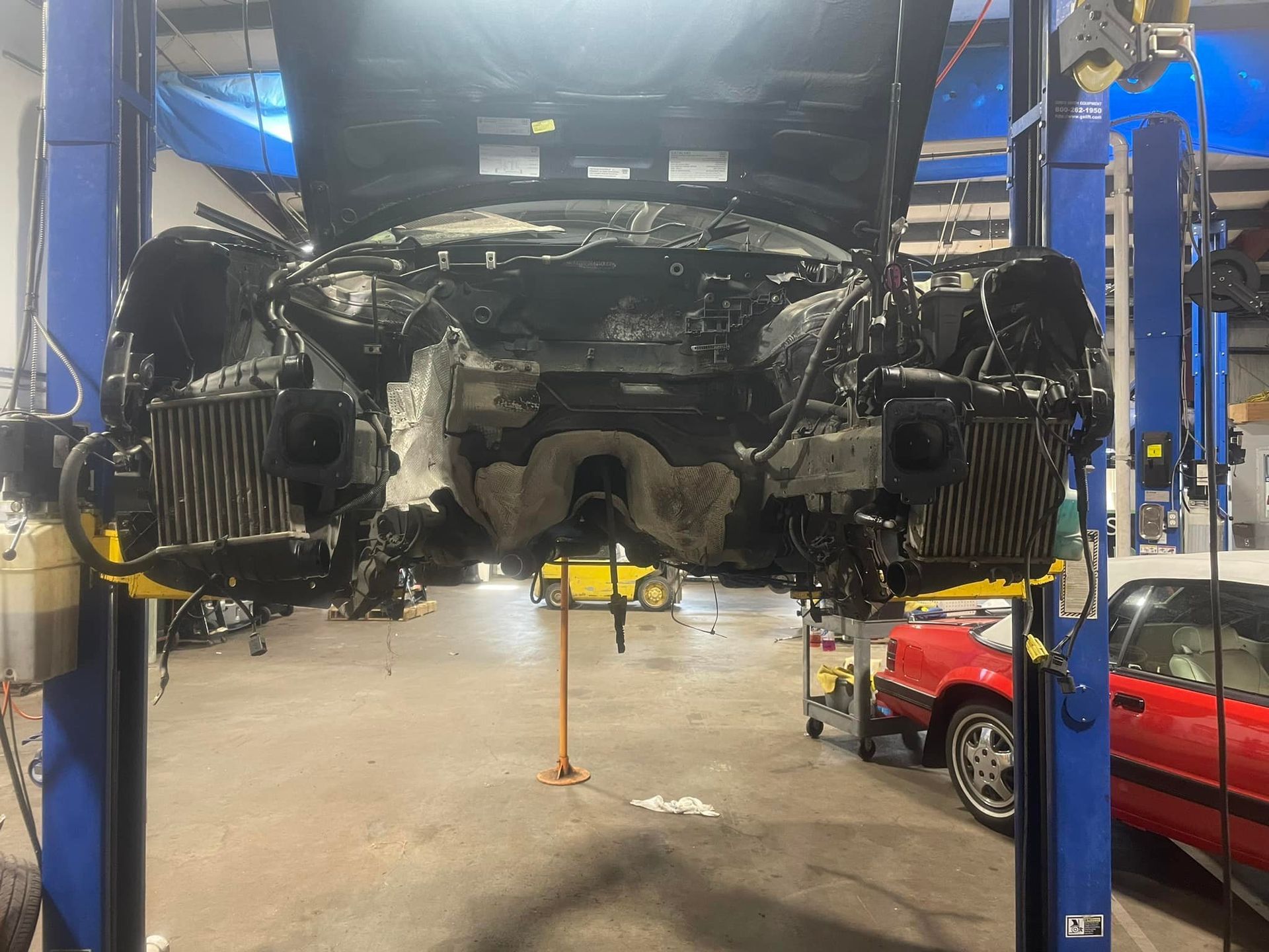 A car is being worked on on a lift in a garage.