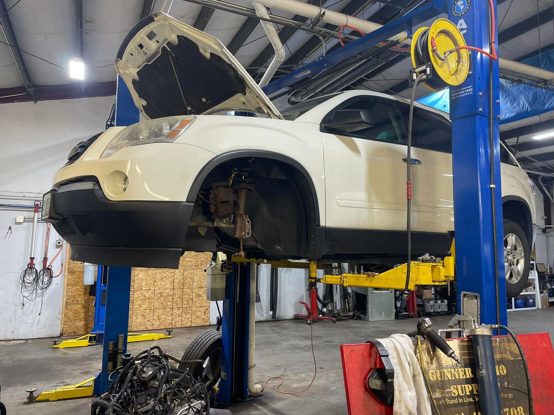 A white car is sitting on a lift in a garage.