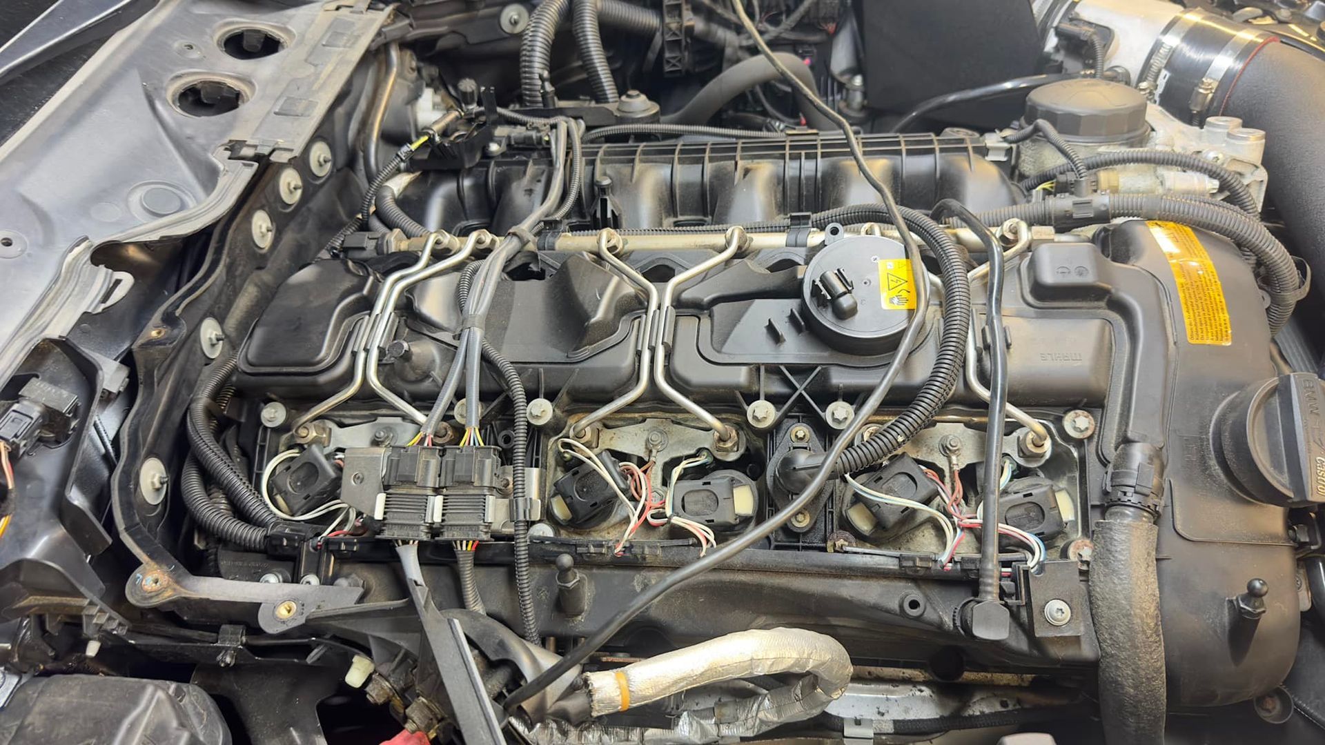 A close up of a car engine with a lot of wires coming out of it.