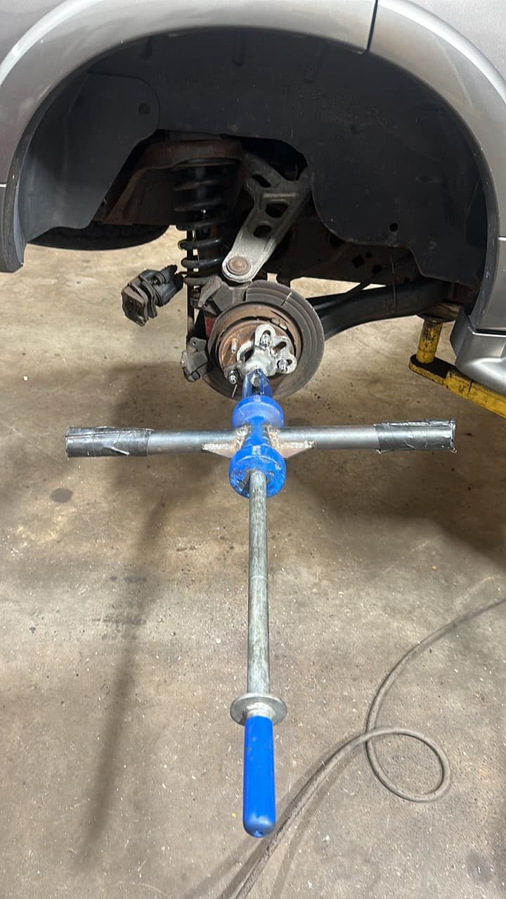 A car is being worked on in a garage with a wrench.