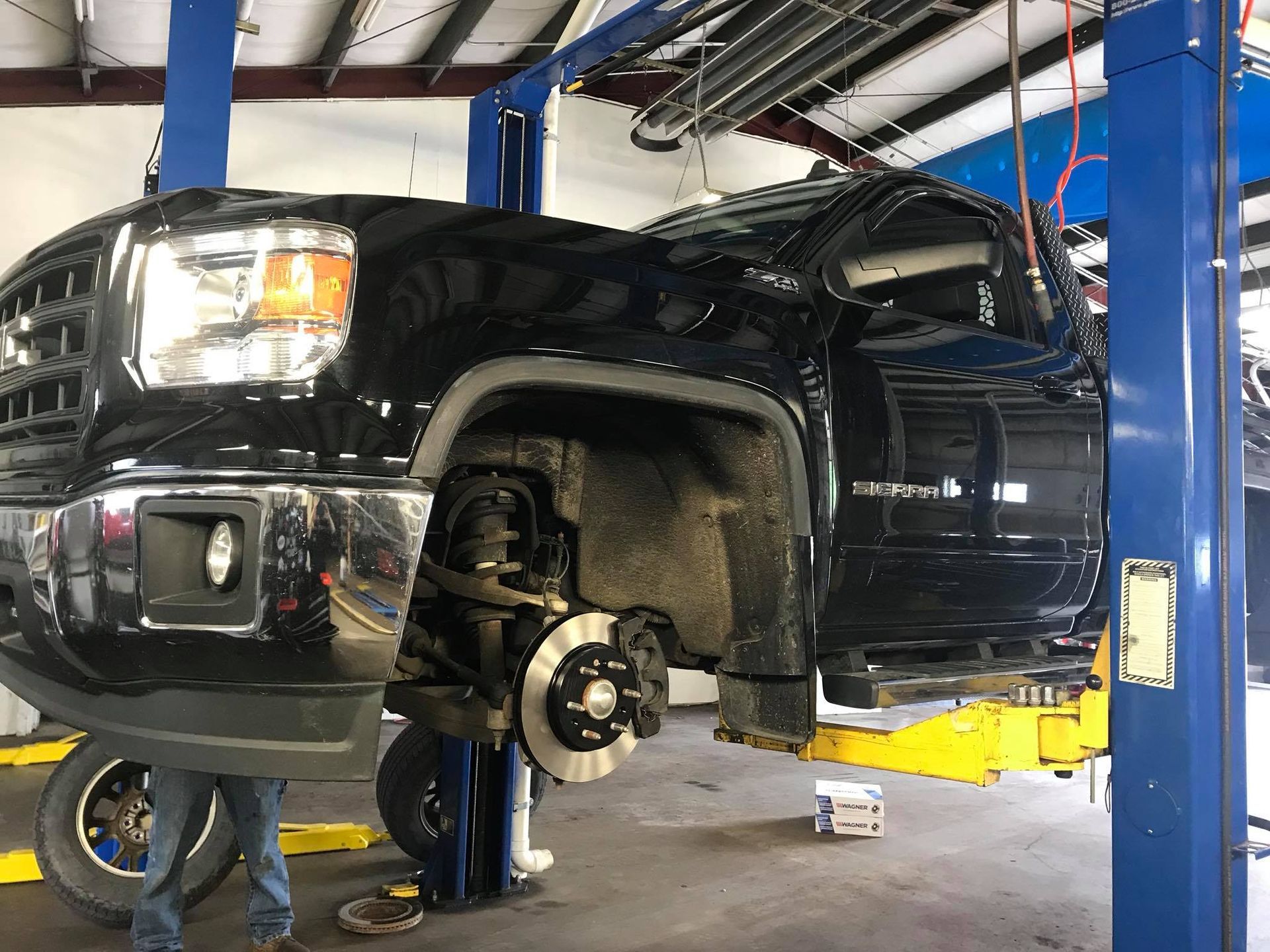 A black truck is sitting on a lift in a garage.
