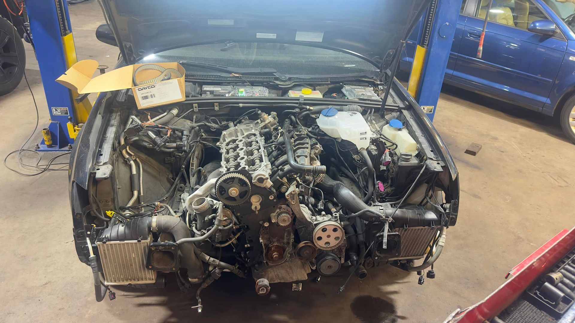 The engine of a car is being removed in a garage