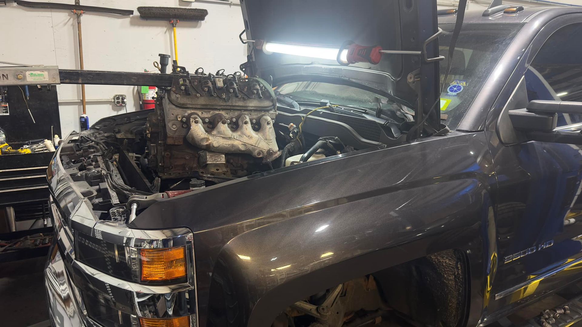 A truck with its hood open is sitting in a garage.