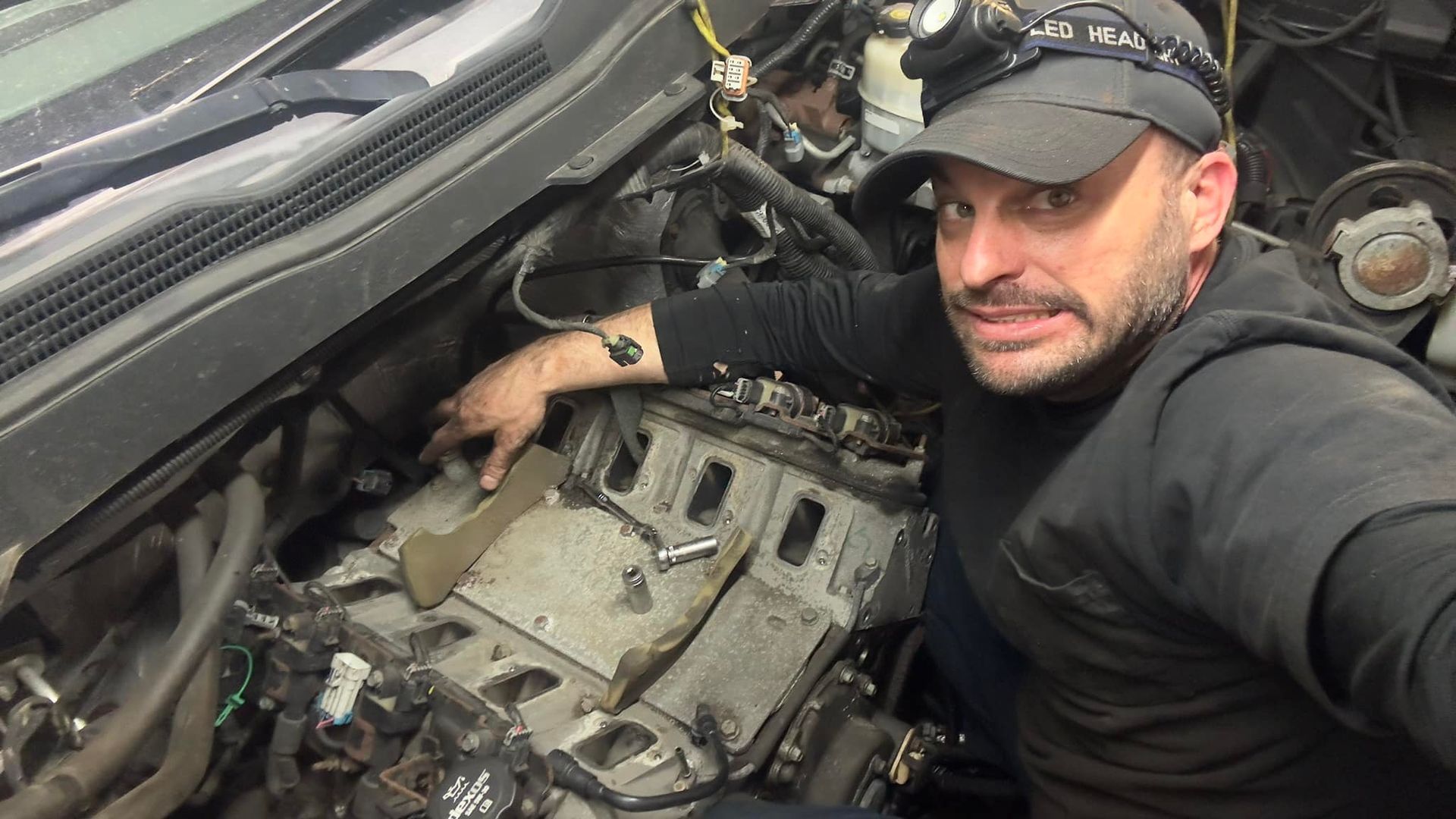 A man is working on the engine of a car.