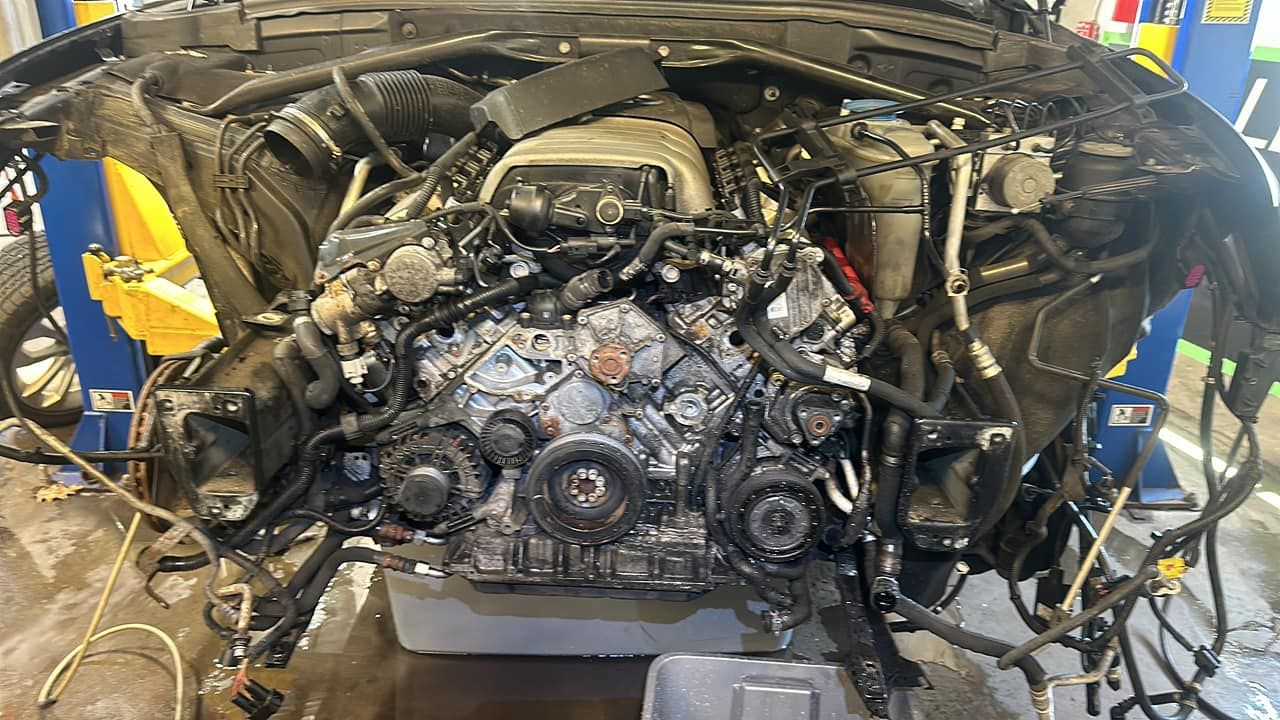 A car engine is sitting on a lift in a garage.