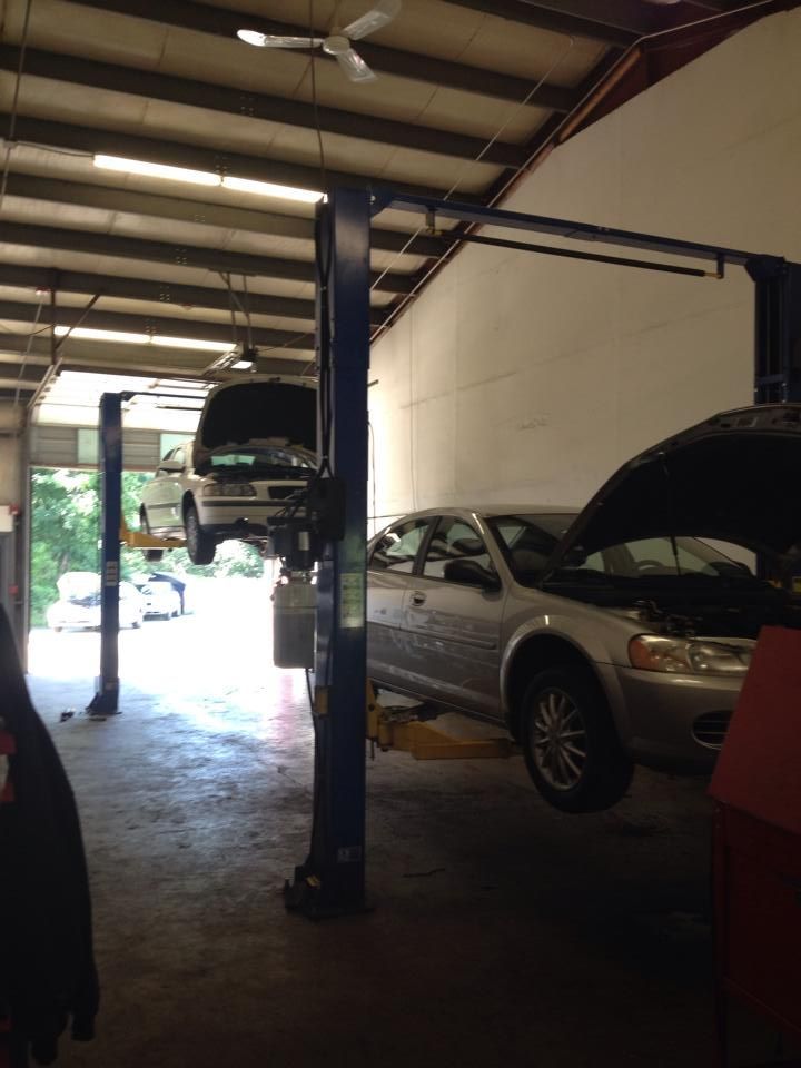 Two cars are on a lift in a garage