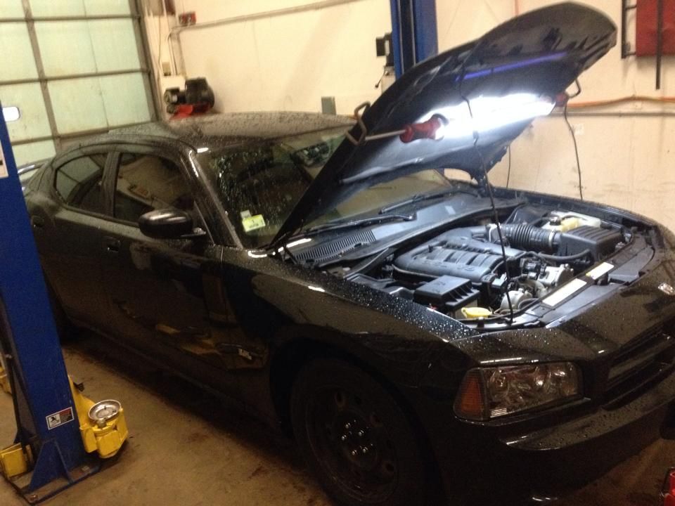 A black car with the hood open in a garage