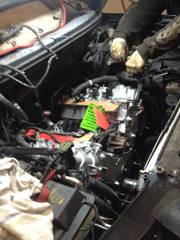 A man is working on the engine of a car