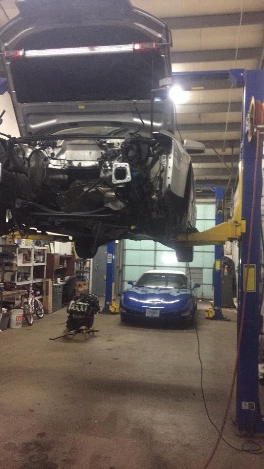 A car is sitting on a lift in a garage.