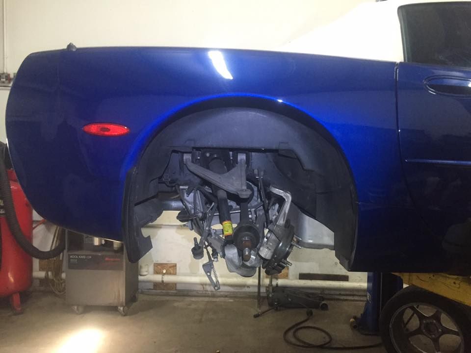 A blue car is sitting on a lift in a garage