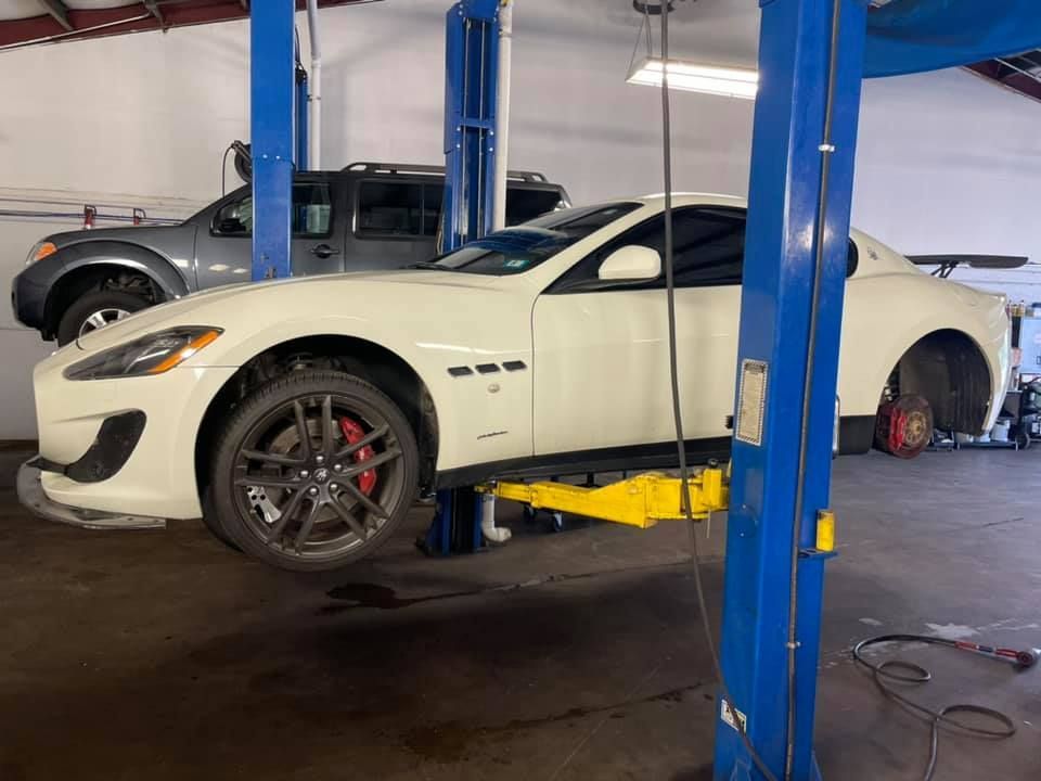 A white car is sitting on a lift in a garage.