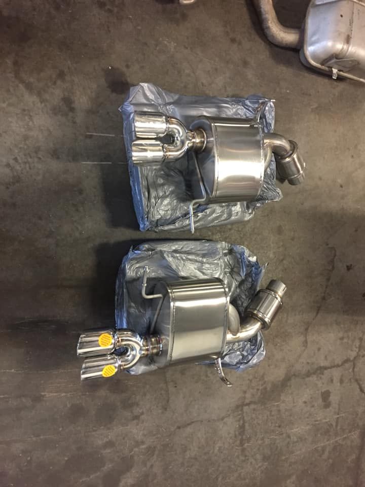 Two exhaust pipes are sitting on top of each other on a concrete floor.
