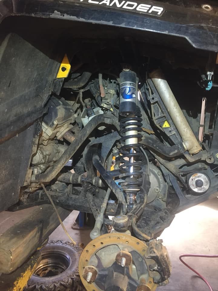 A shock absorber is being removed from a vehicle.