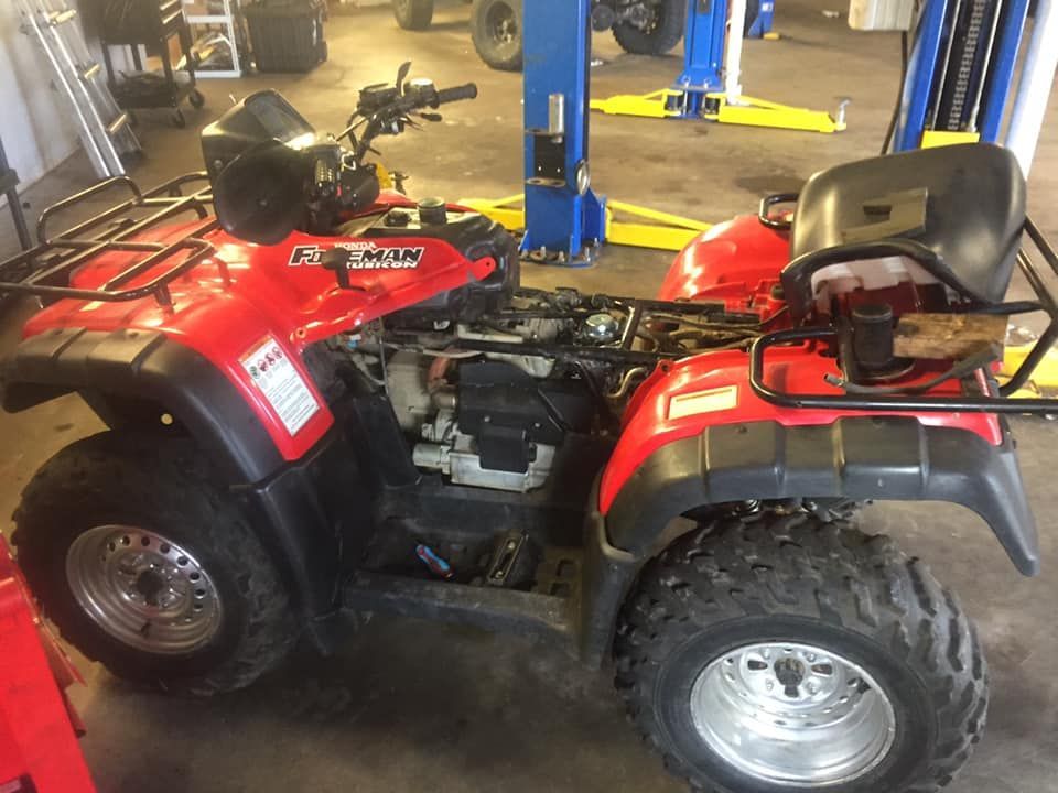 A red atv is sitting on a lift in a garage.
