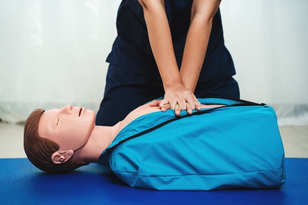 Person performing chest compressions on a manikin during CPR training session
