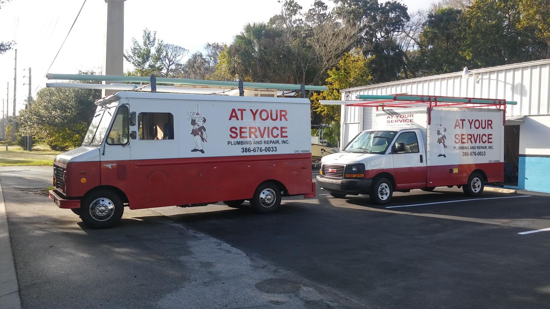 Two red and white service trucks parked on asphalt;