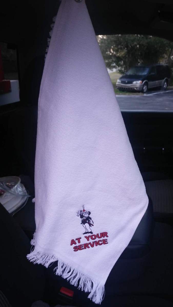 White towel with fringe hanging in a car, embroidered with a figure and