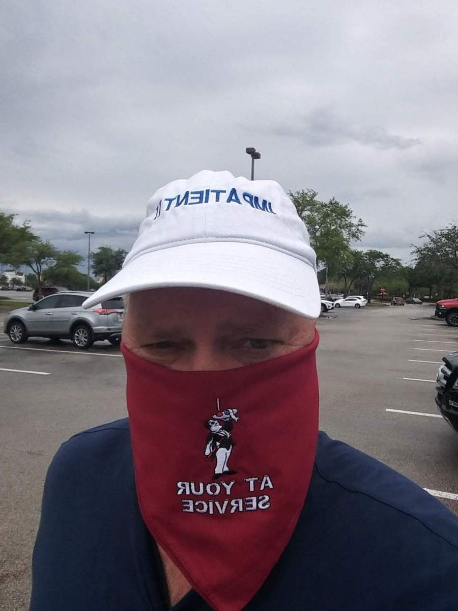 Person in hat and bandana in a parking lot. The bandana says