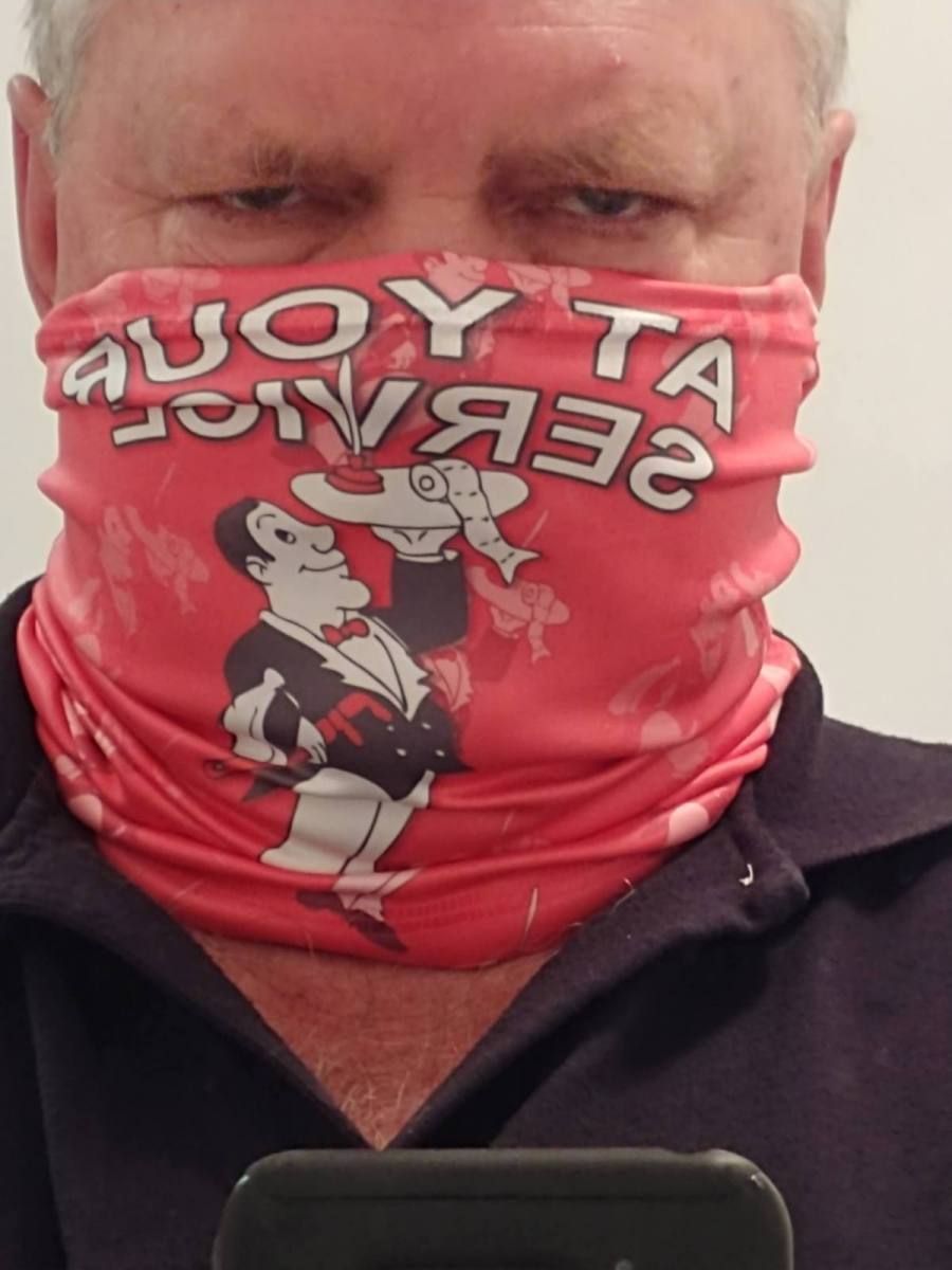 Man wearing a red neck gaiter with a cartoon waiter and text