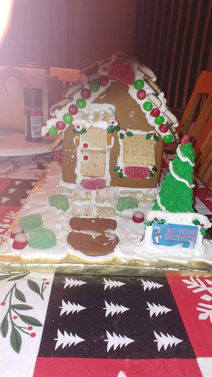 Gingerbread house with white icing and candy decorations on a table.