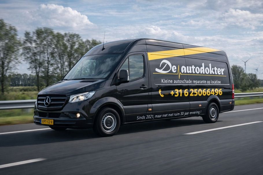 Een zwarte bestelbus met het logo en telefoonnummer van 