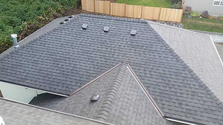 An aerial view of a roof of a house with a wooden fence in the background taken by Riverside Roofing