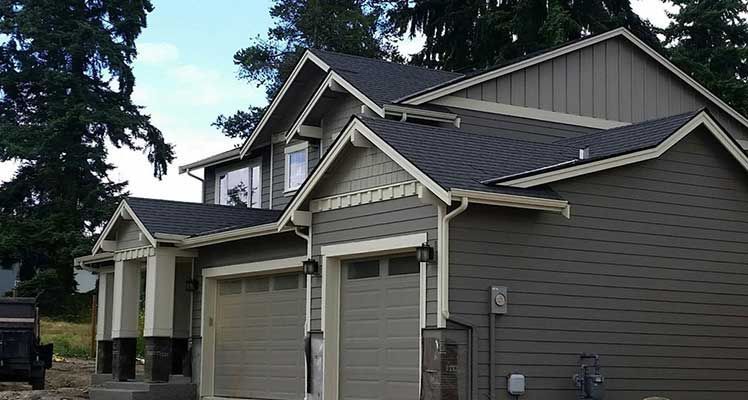 A large house with two garages and a car parked in front of it taken by Riverside Roofing