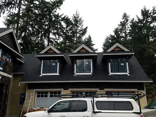 A white truck is parked in front of a house with a black roof taken by Riverside Roofing